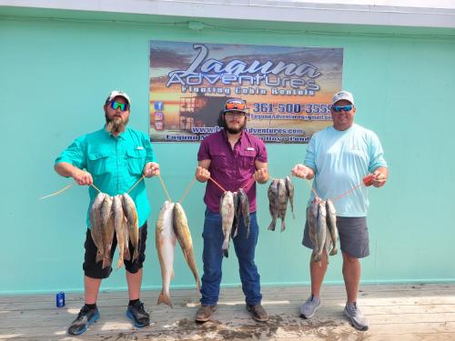 a group of three men holding up their fish at Baffin Bay Penthouse in Corpus Christi
