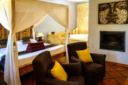 a bedroom with a canopy bed and two chairs at Masía Durbá Hotel in Castellnovo