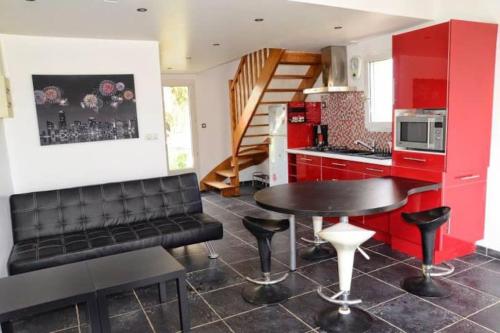 une cuisine avec des placards rouges et une table et un tabouret noirs dans l'établissement Maison dans son écrin de verdure, à Plouvien