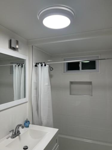 La salle de bains blanche est pourvue d'un lavabo et d'un miroir. dans l'établissement A new Renovated cozy three Bedrooms APT, à Pawtucket