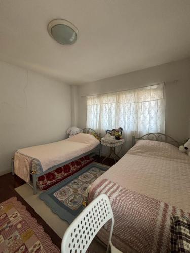 a bedroom with two beds and a chair and a window at Soft Power Host House in Ban Ko