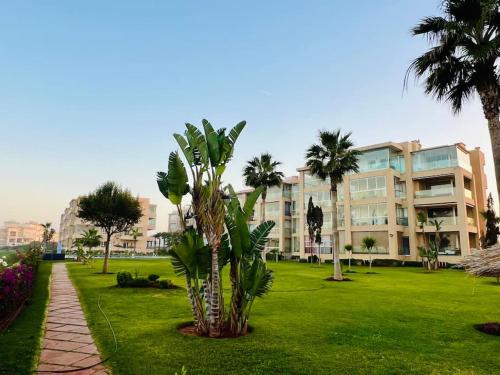 eine Palme in einem Park neben einem Gebäude in der Unterkunft Bouznika, Seaside Escape - Surf, Relaxation, Pools - at StayInMoroccoVibes in Bouznika