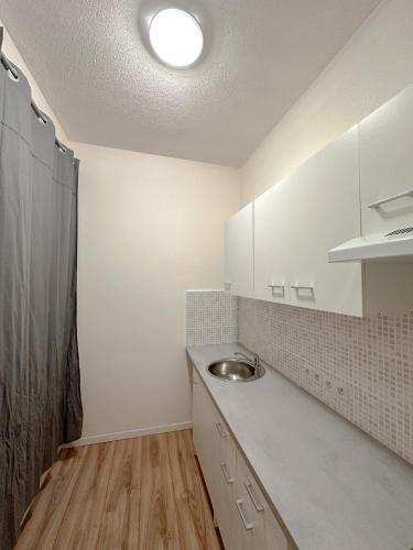 une cuisine avec des armoires blanches et un évier dans l'établissement Studio Urbain Cosy-Touche Rétro, à Perpignan