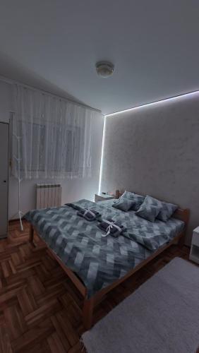 a bedroom with a bed with a blue and gray blanket at Apartman Nikola in Žarkovo