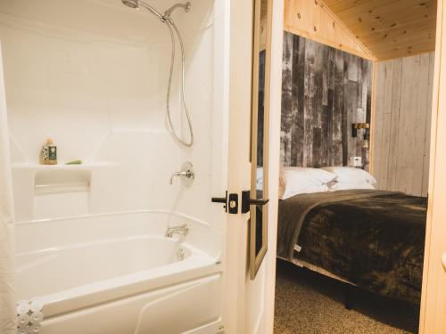 uma casa de banho com uma banheira ao lado de uma cama em Chalet - Abenaki Aventure em Pierreville