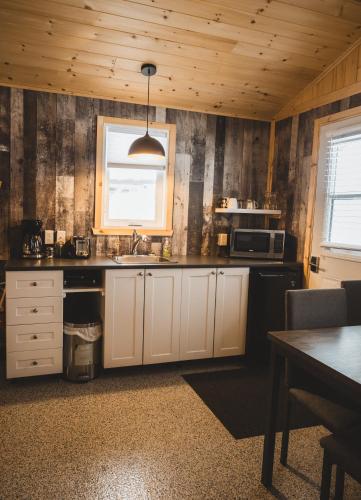 a kitchen with white cabinets and a sink and a window at Mini-Chalet - Abenaki Aventure in Pierreville