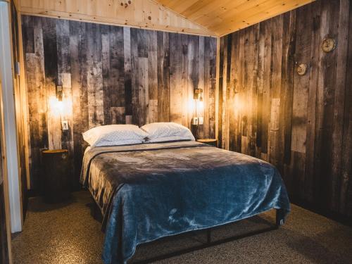 1 dormitorio con 1 cama en una habitación con paredes de madera en Chalet - Abenaki Aventure, en Pierreville