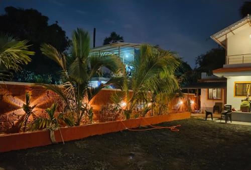 a house with palm trees in front of it at night at Ram Villa Alibag in Ambepur