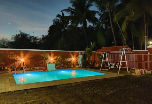 a swimming pool in a backyard at night at Ram Villa Alibag in Ambepur