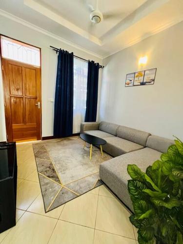 salon z kanapą i stołem w obiekcie 1 Bedroom Apt - The Abode Mori w mieście Dar es Salaam
