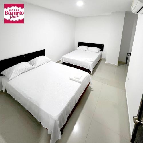 two beds in a room with white walls at Hotel bazurto plaza in Cartagena de Indias