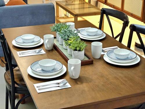 einem Holztisch mit Tellern und Geschirr darauf in der Unterkunft Guest Favorite House in Biñan in Biñan