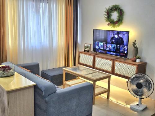sala de estar con sofá azul y TV en Guest Favorite House in Biñan en Biñan