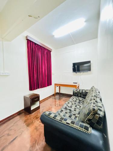 a living room with a couch and a television at Hotel Chetan International in Bengaluru