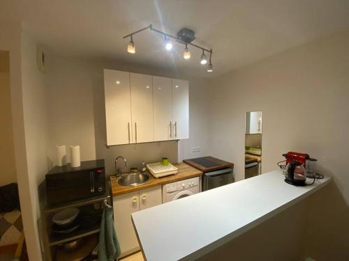 une cuisine avec des armoires blanches et un comptoir dans l'établissement Studio au calme avec jardin proche Paris, à La Garenne-Colombes