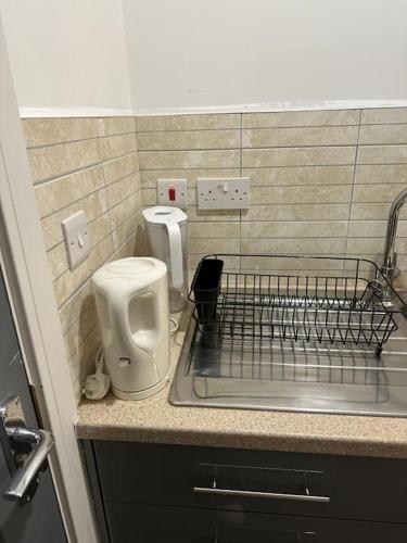 a kitchen counter with a sink and a toilet at cozy studio in Raynes Park House in Raynes Park