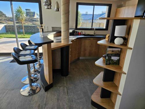 une cuisine avec un comptoir et un bar avec des tabourets dans l'établissement Maison 3 chambres à 350m de la plage avec jardin proche Portbail, à Portbail