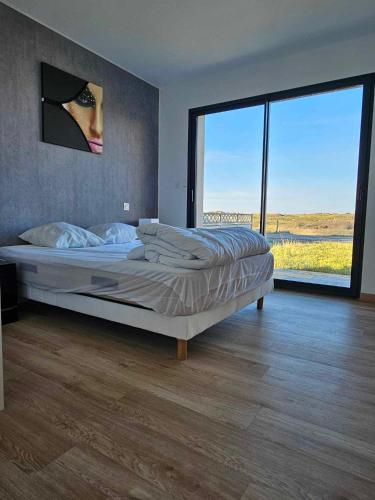 une chambre avec un grand lit et une grande fenêtre dans l'établissement Maison 3 chambres à 350m de la plage avec jardin proche Portbail, à Portbail