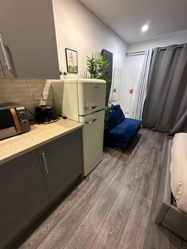 a kitchen with a refrigerator and a blue couch at cozy studio in Raynes Park House in Raynes Park