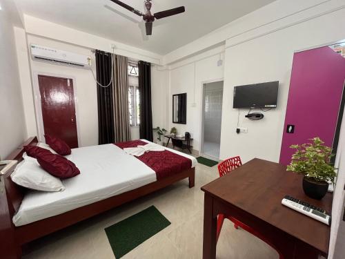 um quarto com uma cama, uma secretária e uma televisão em USC Home Stay-304 em Guwahati
