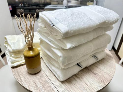 a stack of white towels on a table with a vase at 2名様におすすめ 山手駒込駅徒歩3分 Switch付き池袋新宿秋葉原上野浅草渋谷 in Tokyo
