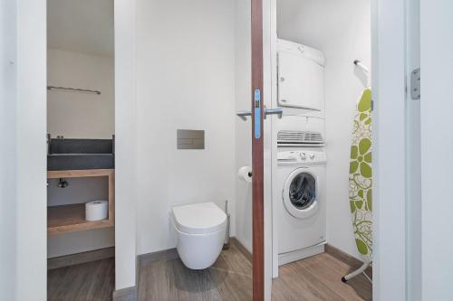 a bathroom with a toilet and a washing machine at Luxury Beachfront Villa 4p - Uitzicht op de Baai & Duinen - Villa 19 in Ouddorp