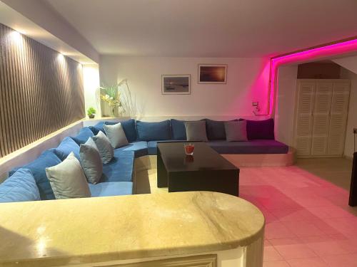 un soggiorno con divano blu e illuminazione rosa di Elegant Relaxing Oasis in the Heart of Sfax a Sfax