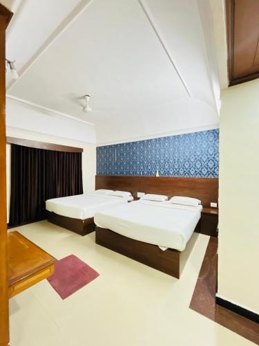 a bedroom with two beds and a blue wall at Hotel Chetan International in Bengaluru