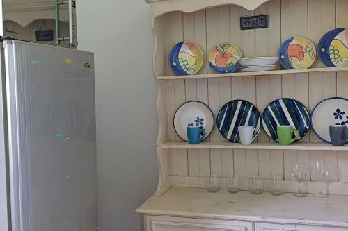 a shelf filled with plates and cups and a refrigerator at River Studio in Barrydale