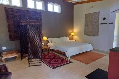 a bedroom with a white bed and a room with windows at River Studio in Barrydale