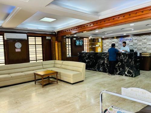 a lobby with a couch and two men standing at a counter at Hotel Chetan International in Bangalore