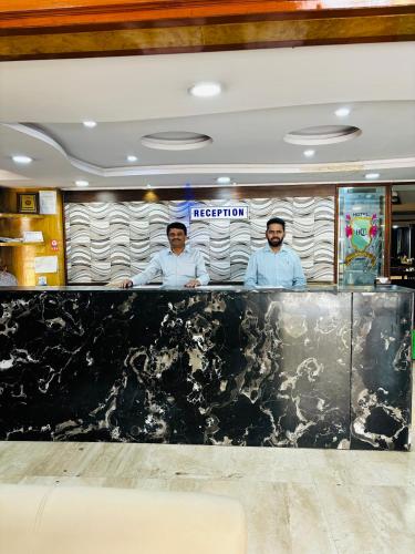 three men standing behind a counter in a restaurant at Hotel Chetan International in Bengaluru