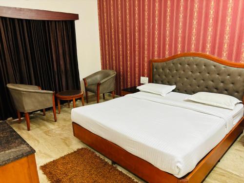 a bedroom with a bed and chairs in a room at Hotel Chetan International in Bengaluru