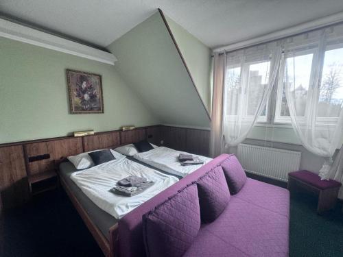 małe łóżko w pokoju z fioletową podłogą w obiekcie Penzion Landštejnský dvůr w mieście Slavonice