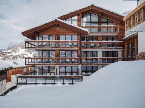 ein Haus im Schnee mit einem Haufen Schnee in der Unterkunft Petit Chalet by Schönegg in Zermatt