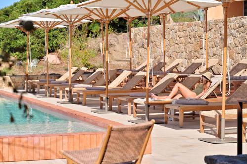 une femme assise sur des chaises longues à côté d'une piscine dans l'établissement Hôtel Abbartello, à Olmeto