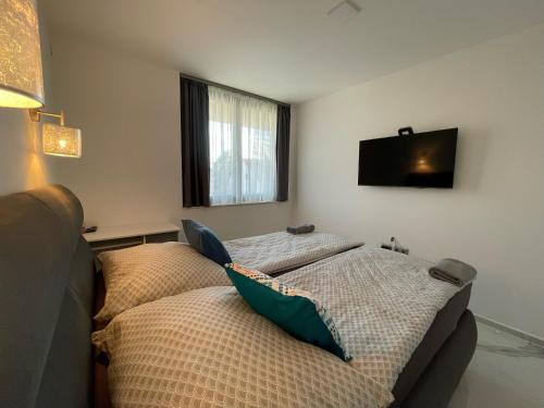 2 camas en una habitación con TV en la pared en Luxury Apartments in Balatonalmádi, Almádi Lux Apartman II - Crystal White, en Balatonalmádi