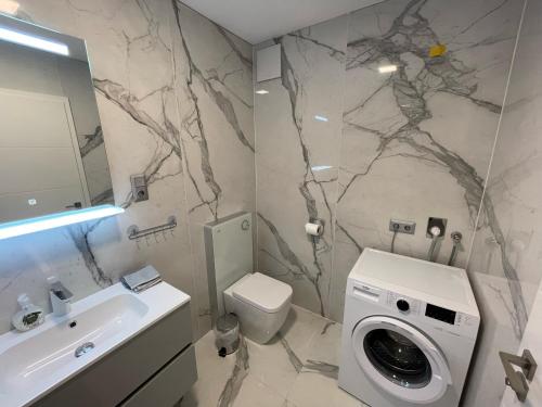 y baño con lavabo y lavadora. en Luxury Apartments in Balatonalmádi, Almádi Lux Apartman II - Crystal White, en Balatonalmádi