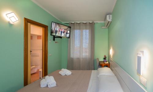 a bedroom with two beds and a tv on the wall at Hotel Villa Benvenuti in Viareggio