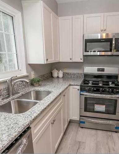 a kitchen with white cabinets and a stove and a sink at Private suite near Cleveland Clinic in Shaker Heights