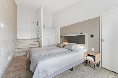 a white bedroom with a large bed and a table at Seaside Panorama Villa 6p - Direct aan de Baai - Villa 37 in Ouddorp
