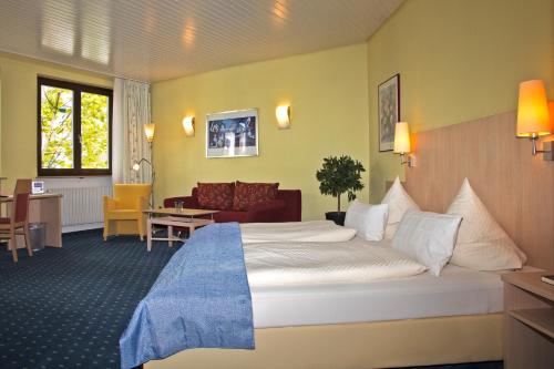 um quarto de hotel com uma cama grande e uma sala de estar em Hotel Deutsches Haus em Lampertheim