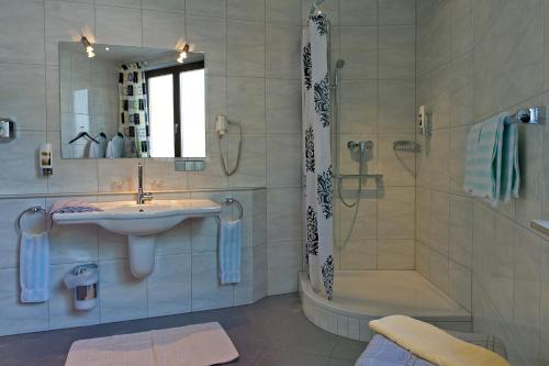 uma casa de banho com um lavatório, um chuveiro e uma banheira em Hotel Deutsches Haus em Lampertheim
