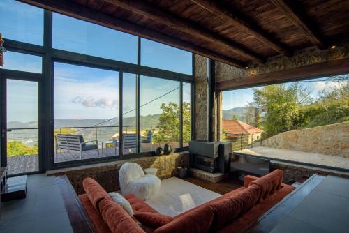 a living room with large windows and a tv at Heartbeat Mountain Escapes in Kato Trikala Korinthias