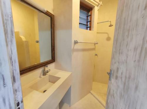 ein Bad mit einem Waschbecken und einem Spiegel in der Unterkunft Apartment on the Sand in Watamu
