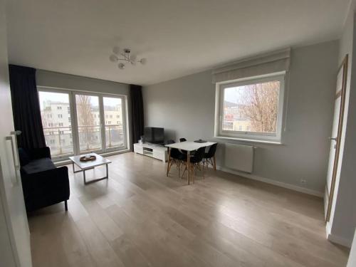 een woonkamer met een tafel en 2 ramen bij Apartament Atrium in Gdynia