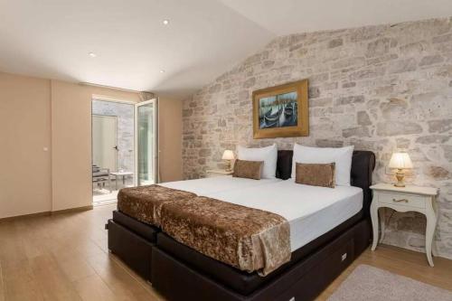 a bedroom with a large bed with a stone wall at Villa Ema in Tar