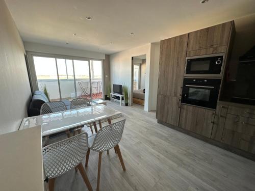 a living room with a table and chairs and a kitchen at Les sables d'or, vue mer, wifi et parking privé in Saint-Hilaire-de-Riez