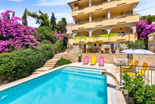 un hôtel avec une piscine en face d'un bâtiment dans l'établissement Villa Penava, private beach, pool and 7min to Trogir, à Trogir