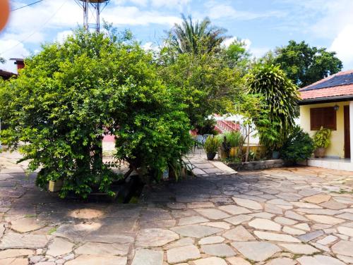 a stone courtyard with trees and a house at Pouso da Lapa in Pirenópolis